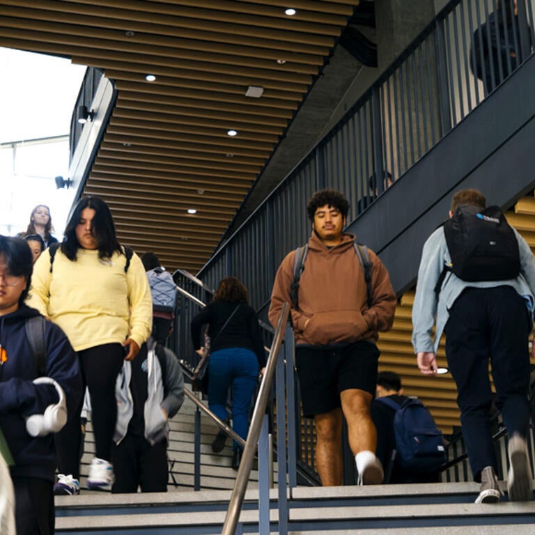 Students on the central staircase inside the modern Student Success Center on the UC Riverside campus.